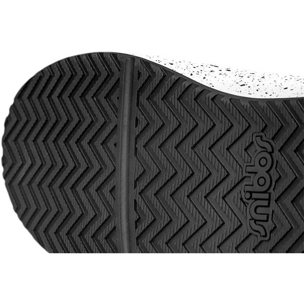 Close-up of black rubber shoe sole with chevron pattern and embossed logo.